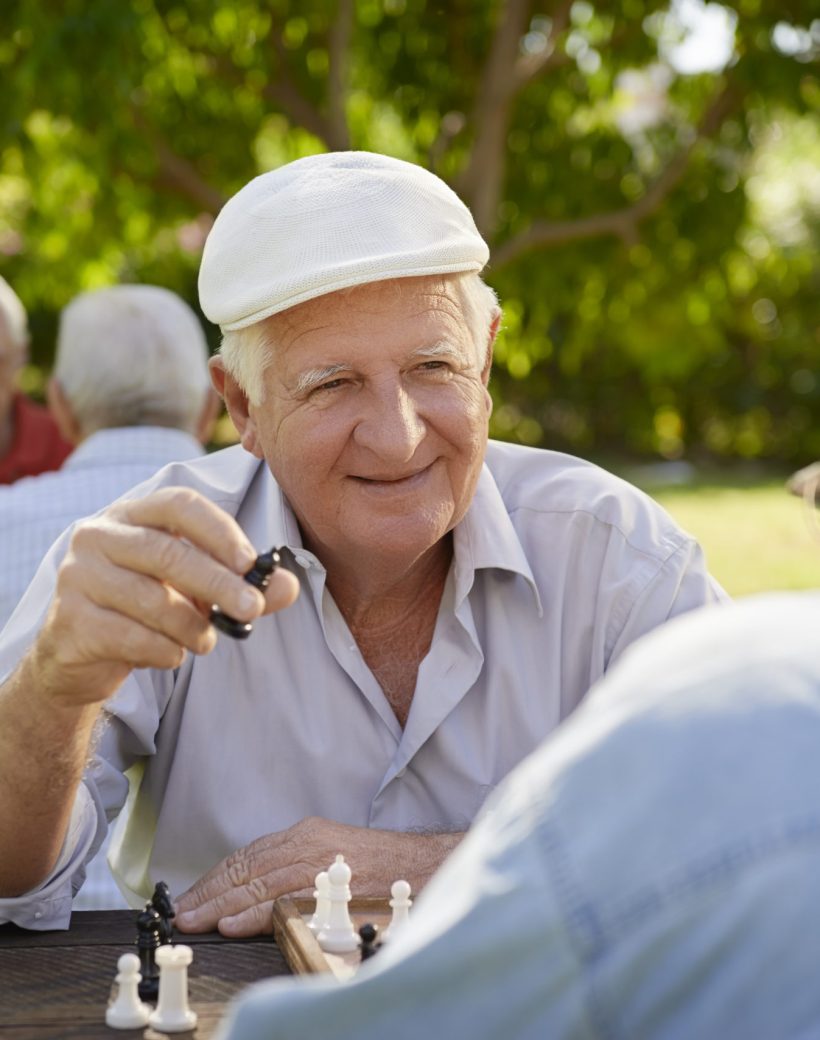 Active retired people, old friends and free time, two seniors having fun and playing chess game at park. Waist up